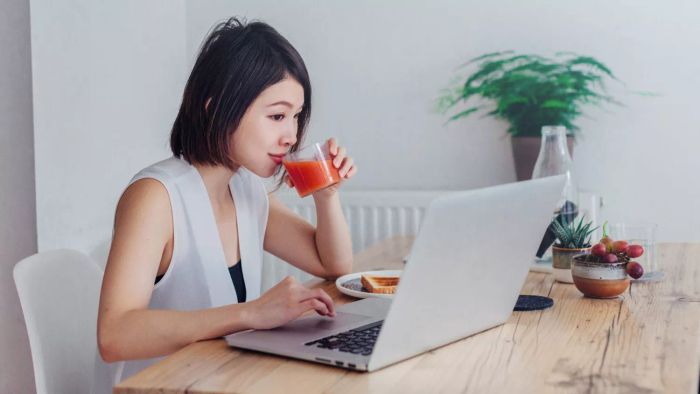 A person sipping juice while organizing a PowerPoint party on their laptop