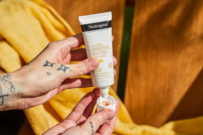 Hands removing the cap from Neutrogena Purescreen+ Mineral UV Tint Face Liquid Sunscreen