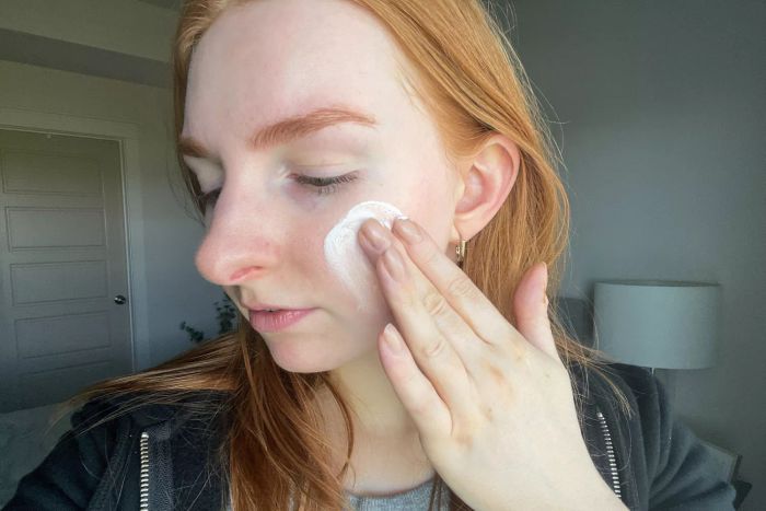 A person applying Colorescience Sunforgettable Total Protection Face Shield Flex SPF 50 to their cheek