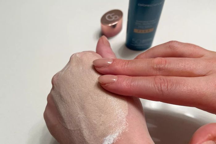 A person blending Colorescience Sunforgettable Total Protection Face Shield Flex SPF 50 into their hand