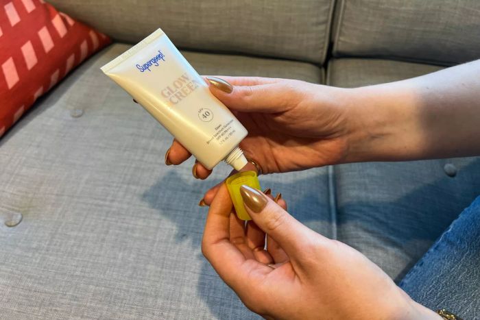 A person opening a tube of Supergoop! Glowscreen