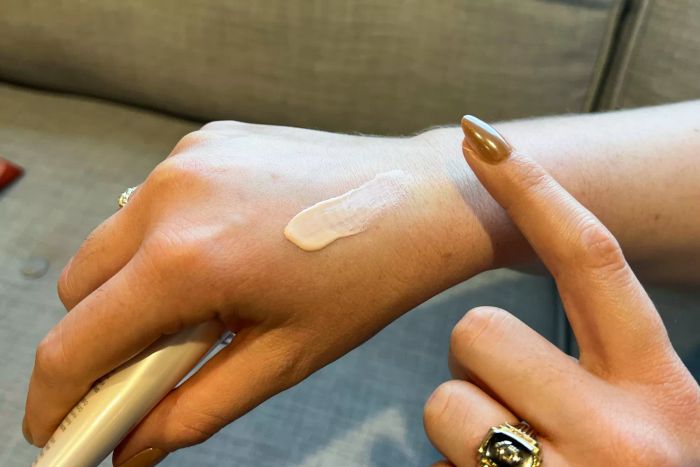 A person applying a line of Supergoop! Glowscreen to the back of their hand