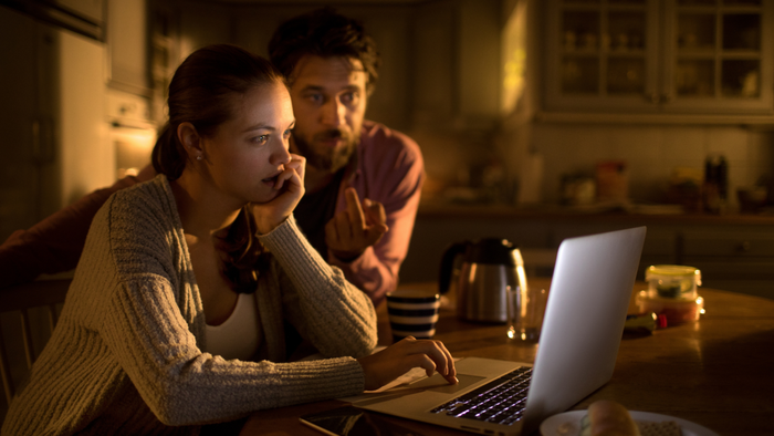 Couple looking overwhelmed while staring at their laptop