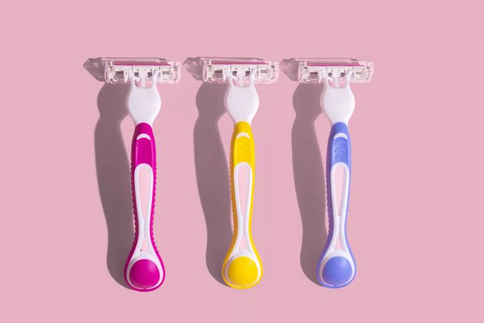 Three razors set against a pink backdrop