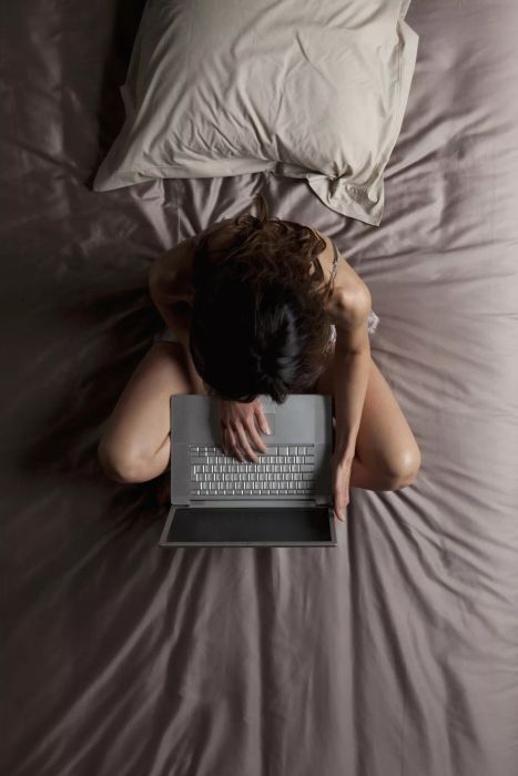 Aerial view of a person using a laptop while seated on a bed