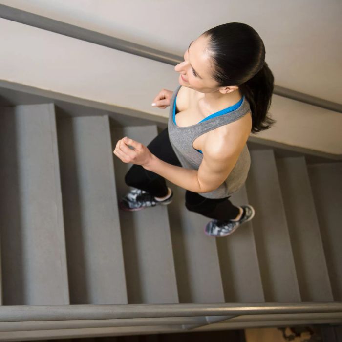 Stair exercise routine, stair exercises at home - trainer demonstration/warm-up (woman working out on stairs inside)