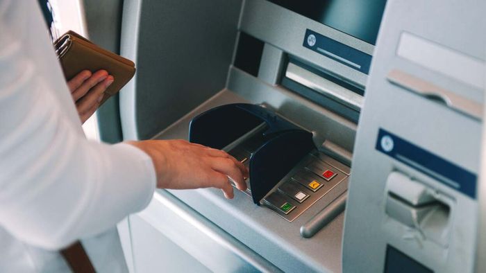 A snapshot of someone's hands interacting with an ATM machine