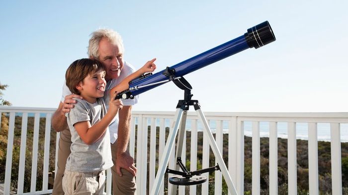 A young boy and his mother observing through a telescope.
