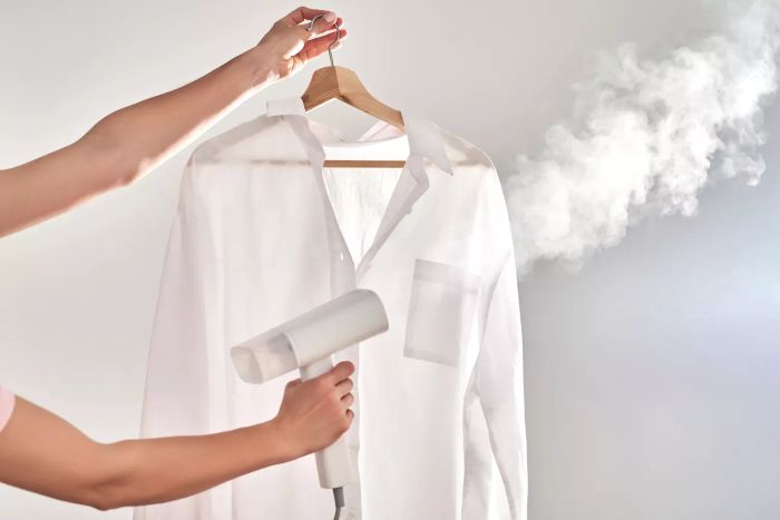 A woman using a steamer on a shirt