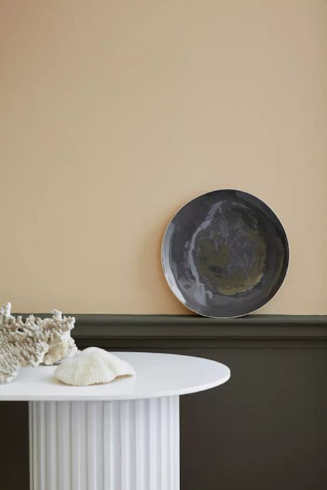 Lute beige paint color on the wall with a white table in front.