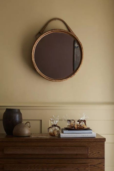 Gold paint on the entryway walls and wainscoting, with a round mirror mounted on the wall.