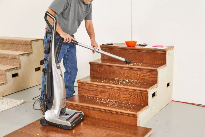 A person is vacuuming wood stairs using the hose of the Kenmore Floor Care Elite Bagged Upright Vacuum.