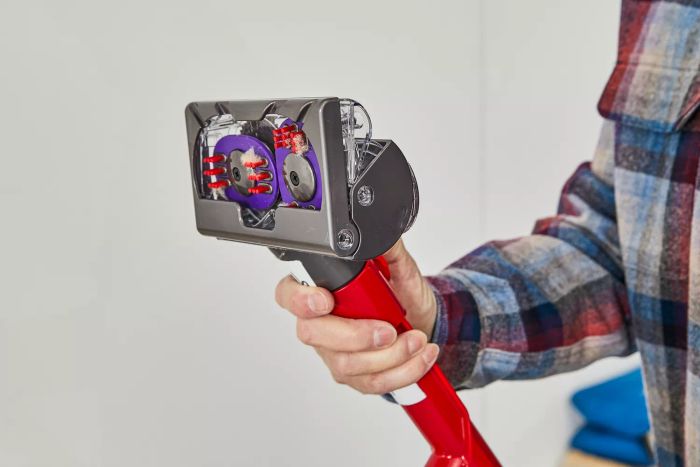 A close-up shot of a person holding the nozzle of the Dyson Ball Animal 3 Extra.