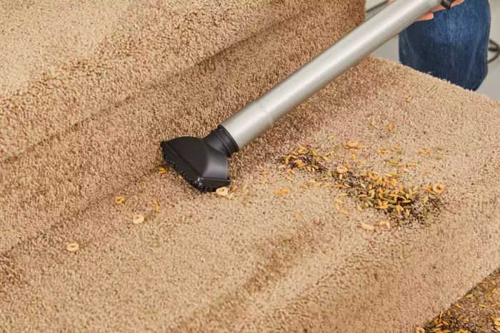 The hose attachment of the Kenmore Floor Care Elite Bagged Upright Vacuum is being used to clean a carpeted step.