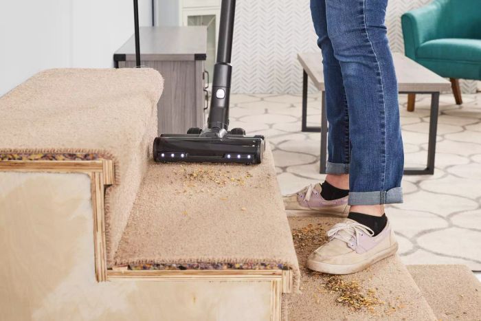 Feet and legs positioned on carpeted stairs while utilizing the Levoit VortexIQ 40 Cordless Stick Vacuum