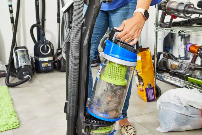 Person lifting a full canister off the Bissell Cleanview Rewind Pet Bagless Vacuum