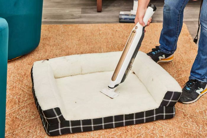A person vacuuming a dog bed with the Shark WS642AE Wandvac Cordless Stick Vacuum
