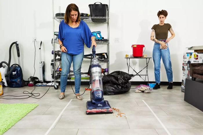 A person is using the Hoover MAXLife Pet Max Complete Upright Vacuum to clean up kibble.
