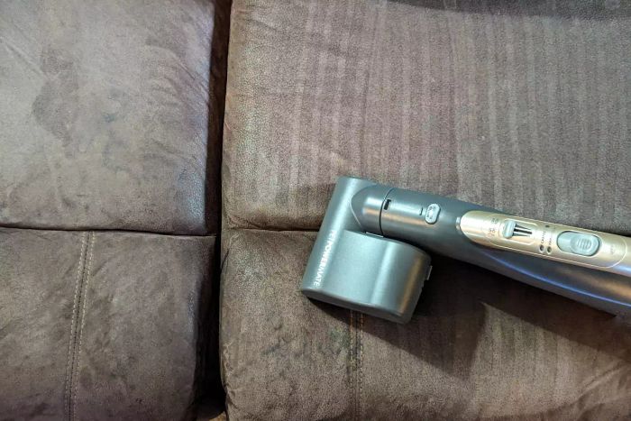A person is vacuuming a couch with the Kenmore Elite 81714 Pet Friendly Canister Vacuum