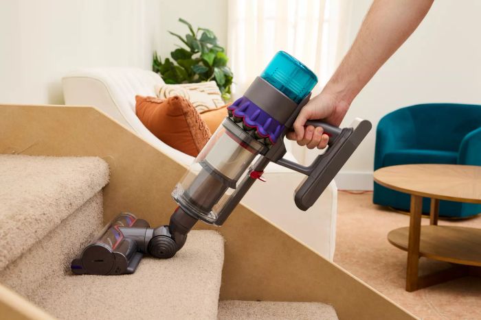 A person is seen cleaning stairs with the Dyson Gen5detect Cordless HEPA Vacuum.