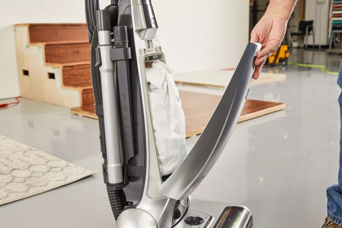 A person is opening the bag compartment of the Kenmore Floor Care Elite Bagged Upright Vacuum.