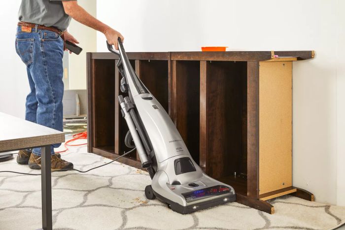 A person is using the Kenmore Floor Care Elite Bagged Upright Vacuum to clean the carpet.