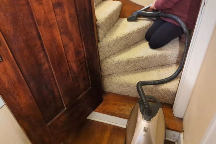 A person is vacuuming the stairs with the Kenmore Elite 81714 Pet Friendly Canister Vacuum