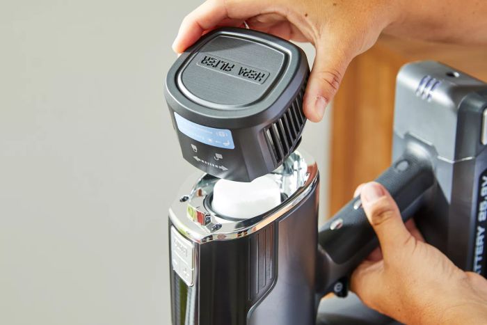 A hand detaching the filter cover from the Levoit VortexIQ 40 Cordless Stick Vacuum