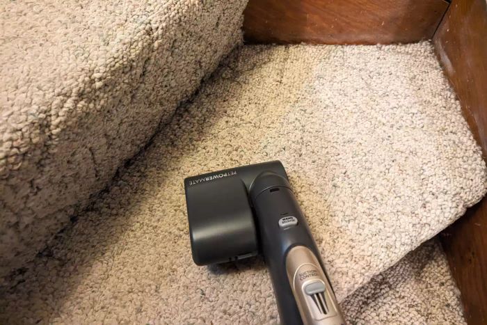 A person uses the Kenmore Elite 81714 Pet Friendly Canister Vacuum to clean carpeted stairs