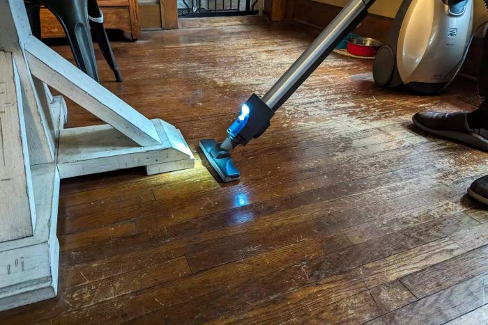 A person is using the Kenmore Elite 81714 Pet Friendly Canister Vacuum to clean a wooden floor