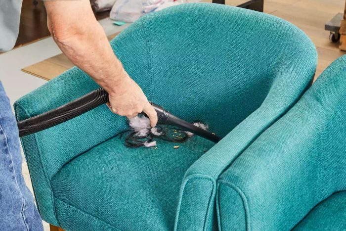 A person is cleaning a chair with the hose attachment from the Kenmore Floor Care Elite Bagged Upright Vacuum.
