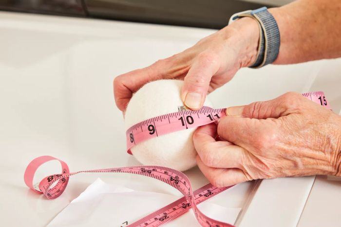 An individual taking measurements of the Everspring 100% New Zealand Wool Dryer Balls