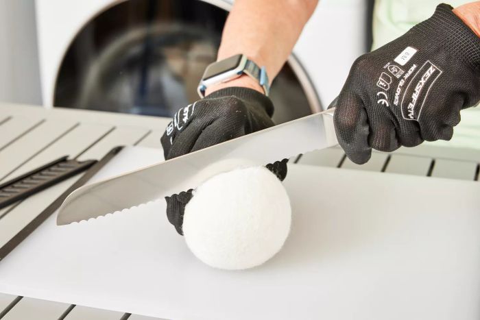 A person is shown using an Everspring 100% New Zealand Wool Dryer Ball during laundry.