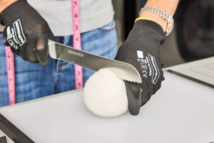 A person cutting the Smart Sheep Wool Dryer Balls in half.