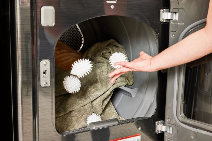 A person tossing the World Market Hedgehog Dryer Balls into a dryer drum