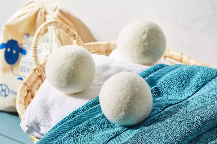 The Handy Laundry Wool Dryer Balls resting on a pile of laundry inside a woven basket