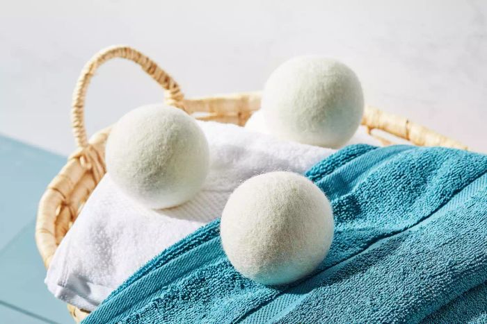 The Grove Co. Wool Dryer Balls resting atop a stack of towels in a handwoven basket