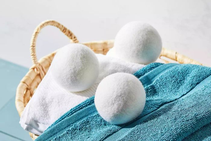 The Everspring 100% New Zealand Wool Dryer Balls rest atop a pile of towels inside a woven basket.