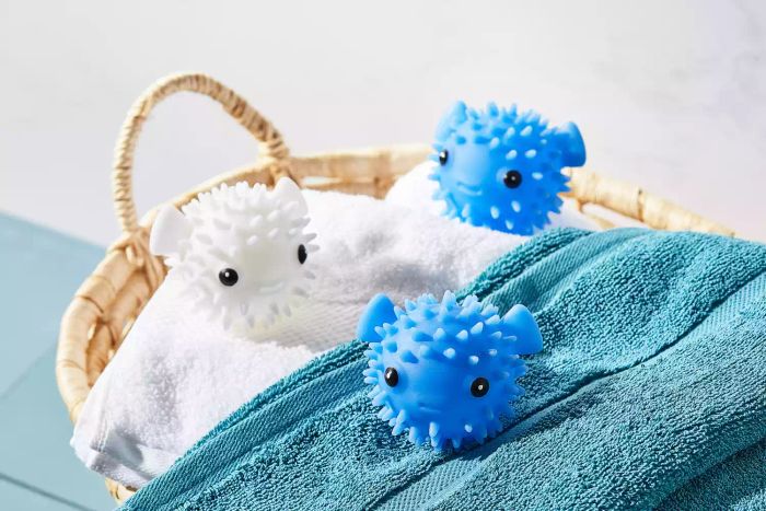 Close-up of the Kikkerland Puffer Fish Dryer Buddies resting on top of a pile of laundry inside a woven basket.