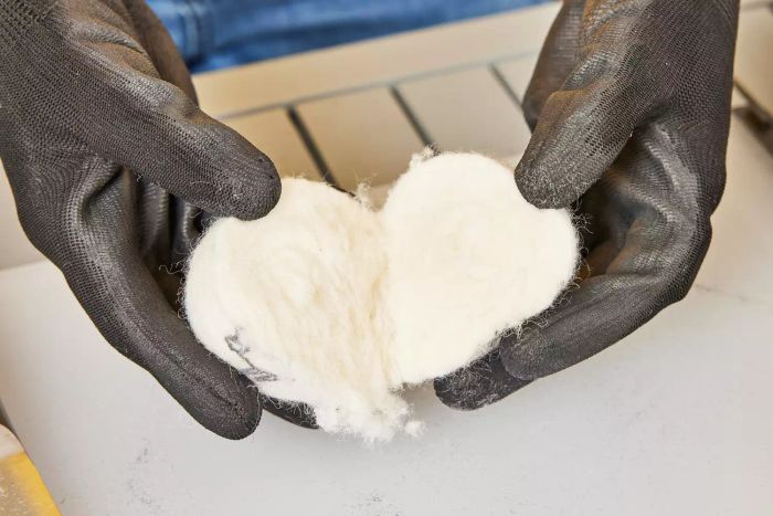 A person holding up a Kainga Recka Wool Dryer Ball, split in half