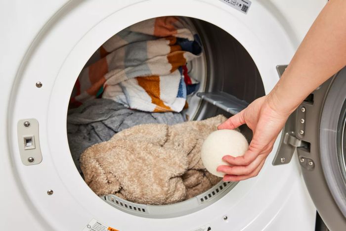 An individual placing the Handy Laundry Wool Dryer Ball into a dryer