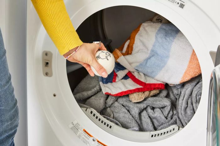 An individual is holding the Kainga Recka Wool Dryer Ball near the dryer.