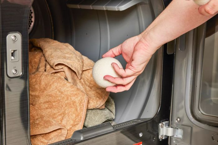 A person placing a Woolzies Organic Wool Dryer Ball into a dryer.