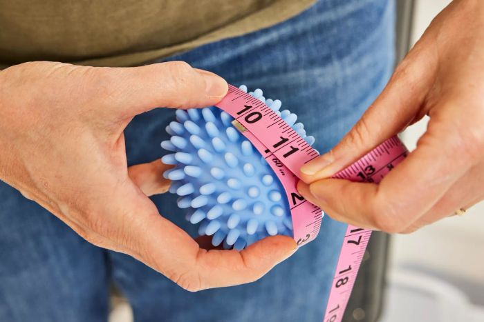 A person measuring the size of a Nellie's Dryerball.