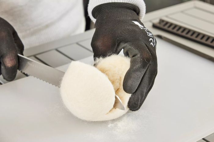 A person slicing the Grove Co. Wool Dryer Balls in half.