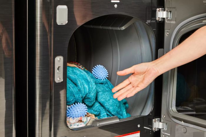 A person placing Nellie's Dryerballs into a dryer