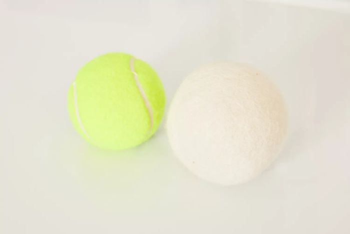 The Handy Laundry Wool Dryer Ball placed next to a tennis ball