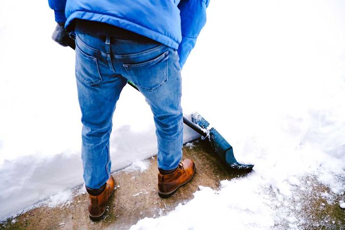 A person shoveling snow by pushing it.