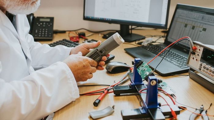 A scientist inspecting the battery compartment of a gadget in his hand
