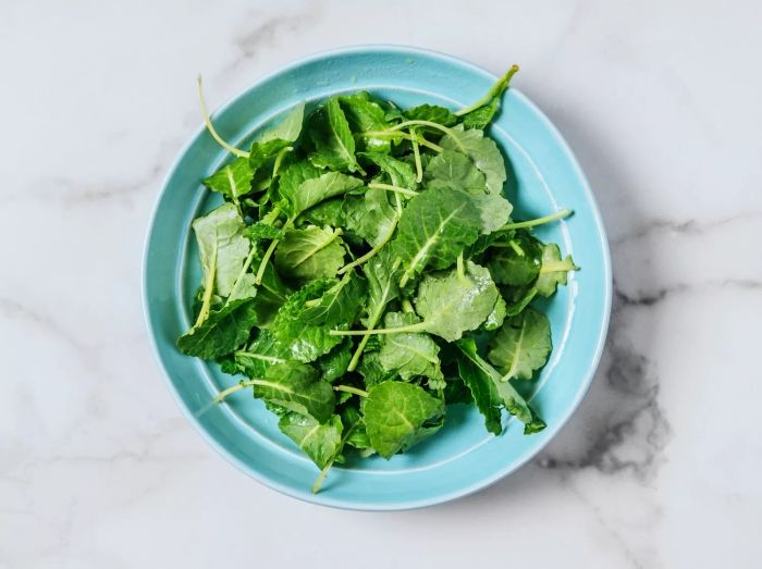 Aerial view of kale leaves placed in a blue bowl.